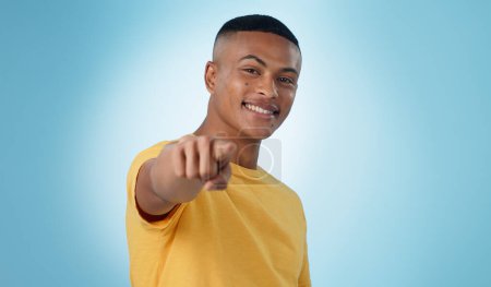 Photo for Man, portrait and pointing to you in studio for choice, vote for winner and decision to volunteer on blue background. Happy model show finger for recruitment, hiring emoji and invitation to join us. - Royalty Free Image