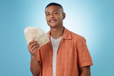 Photo for Young man, winner and money fan with success, bonus or winning in competition, college loan or cashback in studio. Portrait of student with cash, savings and scholarship funding on a blue background. - Royalty Free Image