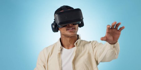 Téléchargez les photos : Homme, étudiant et réalité virtuelle ou lunettes pour l'apprentissage 3D e, vidéo et expérience utilisateur sur fond bleu. Personne ayant une vision VR, une éducation en ligne et une technologie de métaverse pour les jeux en studio. - en image libre de droit