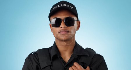 Photo for Security guard, portrait and man in studio with glasses for surveillance, justice and law enforcement on blue background. Serious bodyguard for crime prevention, safety patrol and monitoring danger. - Royalty Free Image