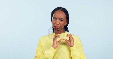 Photo for Woman, portrait and hands of broken heart in studio for sad breakup, depression and lonely emotion on blue background. Unhappy african model show heartbreak emoji for divorce, trauma and pain of love. - Royalty Free Image