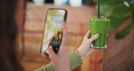 Photo for Phone screen, photography and green juice for diet, woman or glass in cafe for social network app. Influencer girl, smartphone and smoothie in post, update and web blog for nutrition, detox or health. - Royalty Free Image