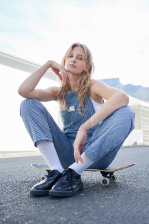 Photo for Cool woman, on skateboard and being outdoor relax, happy and smile with trendy, edgy and stylish look. Female skater sitting, girl and on street or road in summer being chill, active and fresh style - Royalty Free Image