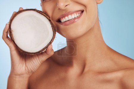 Photo for Happy woman, hands and coconut for skincare, diet or natural nutrition against a blue studio background. Closeup of female person smile with organic fruit for healthy wellness or facial spa treatment. - Royalty Free Image