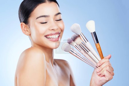 Photo for Makeup, beauty brushes and woman with smile on blue background for cosmetics, powder and foundation. Skincare, cosmetology and face of girl with brush in hands for application, salon and wellness. - Royalty Free Image
