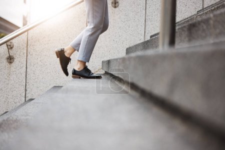 Téléchargez les photos : Escaliers, personne matinale et jambes marchent, voyagent ou en voyage urbain, en plein air ou aller au travail, à destination ou au travail. Étapes de la ville, chaussures d'arrivée et de gros plans, pieds ou escaliers de bâtiment de l'agent grimpant. - en image libre de droit