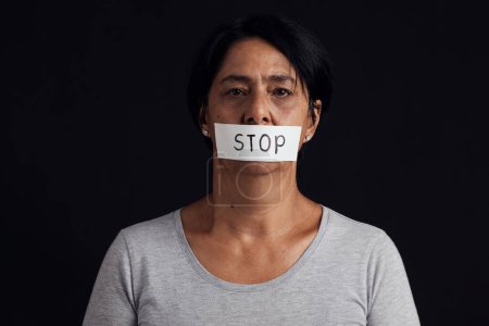 Photo for Portrait, stop and censorship with a woman in studio on a black background for gender equality or domestic violence. Face, silence or abuse and a scared female victim with her mouth covered in fear. - Royalty Free Image