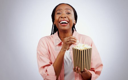 Foto de Retrato, risa o mujer negra viendo una película en estudio para cine con palomitas de maíz para relajarse. Comedia, persona africana divertida o feliz comiendo bocadillos para la transmisión de películas o suscripción en fondo gris. - Imagen libre de derechos