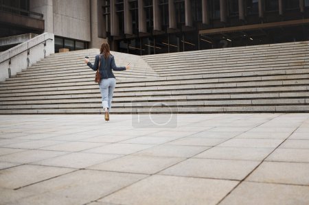 Photo for Walking, travel and business woman in city with ambition for morning commute, journey and building. Professional, growth and back of female person by steps for career progress, work and job in town. - Royalty Free Image