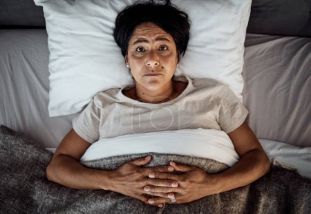 Photo for Insomnia, portrait and senior woman in bed from above with menopause, anxiety or stress in her home. Top view, face and elderly female in a bedroom with depression, trauma or mental health crisis. - Royalty Free Image