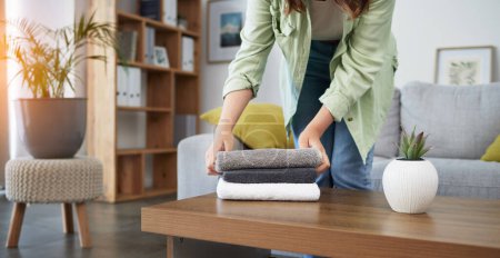 Photo for Cleaning, hands and woman with laundry in a living room for housework, routine or home spring clean. Washing, fold and female person with fresh, towels or linen in a house for household hygiene. - Royalty Free Image