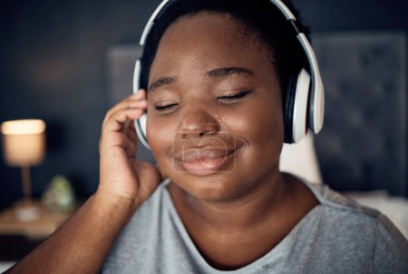 Photo for Crying, happy and black woman with headphones for music, sound or audio. Tears, radio and plus size African person listening, hearing and streaming podcast for peace or relax in home bedroom at night. - Royalty Free Image