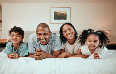 Foto de Feliz, sonrisa y retrato de una familia en una cama para relajarse, descansar y unirse. Felicidad, amor e hijos acostados con su joven madre y padre en el dormitorio de su casa moderna - Imagen libre de derechos