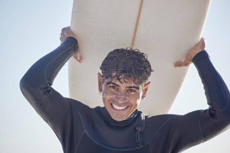 Téléchargez les photos : Portrait, surf et homme surfeur avec planche de surf à la plage, la mer ou l'océan avec un sourire et est heureux un jour d'été. Exercice, surf et homme en maillot de bain en Australie avec liberté sur les vagues. - en image libre de droit