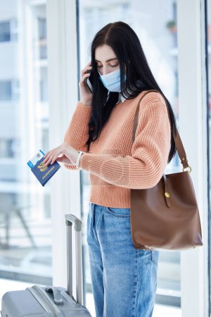 Photo for Covid, travel and passport with woman in face mask and phone call for immigration law, corona virus airport policy. Person with suitcase check time on watch with document problem, covid 19 compliance. - Royalty Free Image