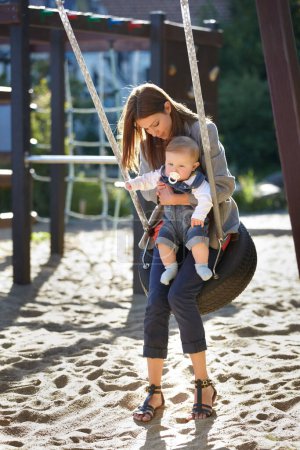 Photo for Mother, baby and swing on park for love, bonding and play with sunshine, child development and care. Woman, kid and infant swinging outdoor in summer for fun, enjoyment and nurture with happiness. - Royalty Free Image