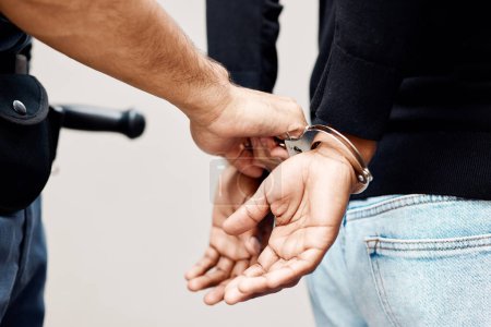 Photo for Man, police and handcuffs on criminal for arrest, crime or justice in theft, robbery or violence in city. Closeup of male person, officer or security guard cuffing hands of suspect, thief or gangster. - Royalty Free Image