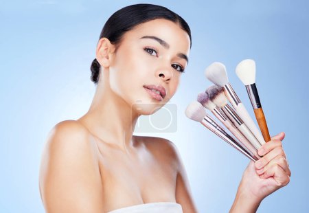 Photo for Makeup, beauty brushes and portrait of woman on blue background for cosmetics, powder and foundation. Cosmetology, salon aesthetic and face of girl with tools for application, wellness and skin glow. - Royalty Free Image