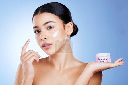 Photo for Skincare, beauty and portrait of a woman with cream isolated on blue background in a studio. Cosmetic, treatment and girl applying a lotion, sunscreen or moisturizer on face for promotion with space. - Royalty Free Image