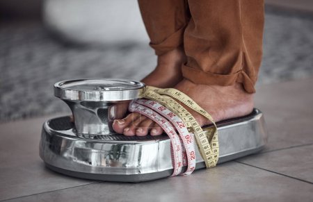 Foto de Pies, anorexia y persona a escala con cinta métrica para comprobar el cuerpo a perder peso con estrés. Equilibrio, pie y resultados de la dieta, obsesión poco saludable y trastorno alimenticio en el hogar, contando calorías. - Imagen libre de derechos