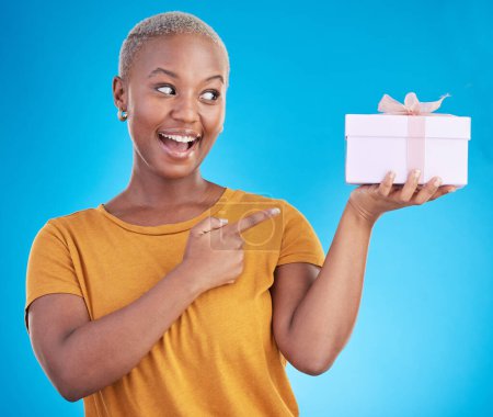 Photo for Gift, excited black woman and pointing at box in studio isolated on a blue background. Promotion, happy or African person with present for party, celebration of holiday or birthday for giveaway prize. - Royalty Free Image