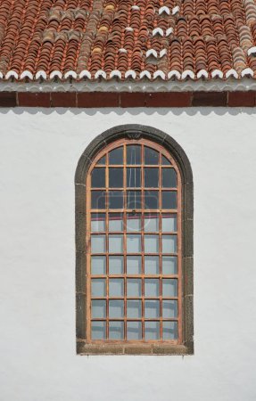 Téléchargez les photos : Architecture d'un mur gris avec une fenêtre cintrée à l'extérieur. Texture extérieure détails d'un ancien bâtiment résidentiel rustique ou une église avec des fenêtres en bois vintage découvert à Santa Cruz de La Palma. - en image libre de droit