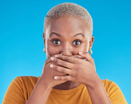Photo for Gossip, secret or portrait black woman shocked by mistake or announcement in studio on blue background. Wow, fake news or surprised girl with excited, wtf or omg expression with hands to cover mouth. - Royalty Free Image