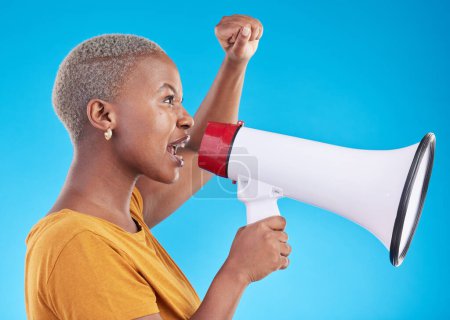 Photo for Black woman, megaphone and protest in studio, shout or profile with fist in air for human rights by blue background. African gen z student, girl and audio tech for power, opinion or news announcement. - Royalty Free Image