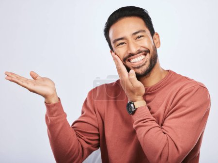 Photo for Hand pointing, smile and portrait of asian man in studio with mockup, promotion or news on a white background. Happy, face and male person with platform for menu, open palm or sale announcement. - Royalty Free Image