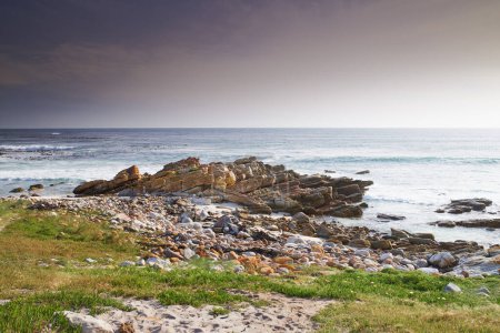 Téléchargez les photos : Un littoral rocheux dans le Cap occidental, Afrique du Sud par une chaude journée d'été. Ciel clair et plages, une escapade parfaite remplie de stations balnéaires et d'activités de bien-être en plein air par temps tropical. - en image libre de droit