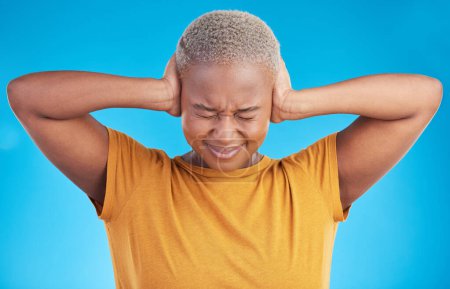 Téléchargez les photos : Stress, maux de tête ou femme noire couvrent les oreilles en studio sur fond bleu avec crise de bruit ou d'anxiété. Conflit, personne effrayée ou fille africaine qui craint un traumatisme, des maux de tête ou une distraction sonore. - en image libre de droit