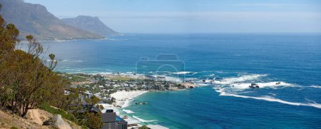 Photo for Panorama of a mountain coastline with quiet ocean against a blue sky in South Africa from above. Scenic wallpaper of a serene landscape of calm waves near Camps Bay with a peaceful sea view - Royalty Free Image