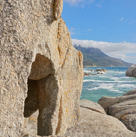 Téléchargez les photos : Paysage rocheux et océanique à Camps Bay, Le Cap, Afrique du Sud. Vue panoramique de gros rochers sur le rivage de la plage en été. Grandes pierres dans la mer à destination touristique célèbre. - en image libre de droit