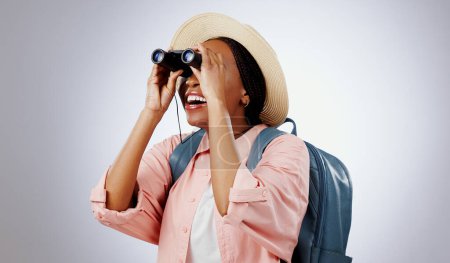 Photo for Woman, binoculars and search on adventure, studio and travel or backpack by gray background. Black person, vacation and holiday in mockup, watch and explore on journey, gear and equipment for tourist. - Royalty Free Image