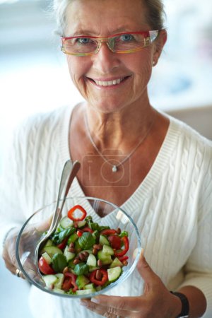 Foto de Retrato, sonrisa y mujer mayor con ensalada para una dieta saludable, nutrición y bienestar en gafas. Cara, persona feliz y tazón de verduras, comida vegetariana orgánica y beneficios, desintoxicación y almuerzo en casa. - Imagen libre de derechos