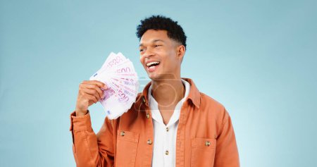 Photo for Happy man, winner and money fan with success, bonus or winning, college loan or cashback ideas in studio. Excited student thinking of cash, savings or scholarship funding isolated on blue background. - Royalty Free Image