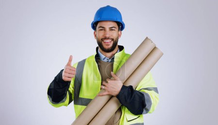 Photo for Engineering, man and thumbs up for architecture success, renovation and design planning with blueprint in studio. Portrait of construction worker or contractor with like emoji on a white background. - Royalty Free Image