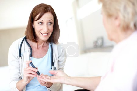 Photo for Dont worry, this wont hurt a bit. Mature nurse checking an elderly patients blood sugar levels with a prick to the finger - Royalty Free Image