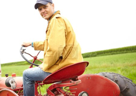 Foto de Sólo un día normal en la oficina. Retrospectiva de un granjero sonriente conduciendo su tractor en un campo abierto - Imagen libre de derechos
