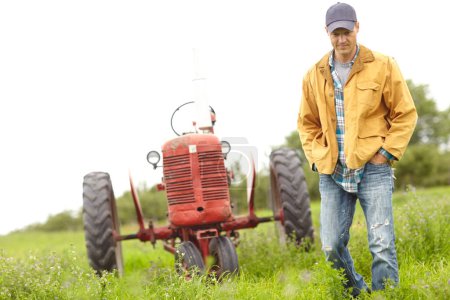 Téléchargez les photos : Promenade nature. Image pleine longueur d'un agriculteur debout à côté de son tracteur dans un champ - en image libre de droit