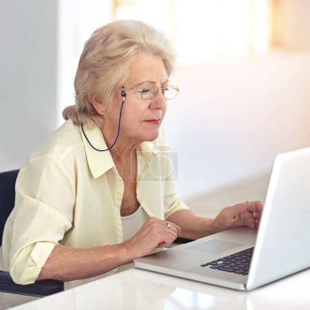 Photo for Staying in touch with all her friends. a senior woman using her laptop at home - Royalty Free Image