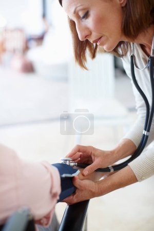 Photo for Clinical and professional examination. Closeup of a mature nurse checking the blood pressure of her patient - Royalty Free Image