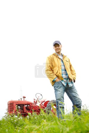 Téléchargez les photos : L'un des avantages d'être un agriculteur Nature. Portrait complet d'un agriculteur debout dans un champ avec un tracteur garé derrière lui - Copyspace - en image libre de droit
