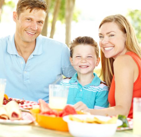 Téléchargez les photos : Profiter d'un déjeuner en famille. Une jeune famille heureuse se relaxant dans le parc et profitant d'un pique-nique sain - en image libre de droit