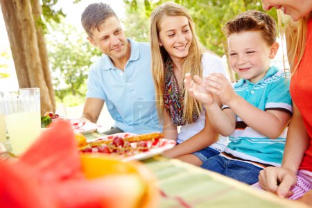 Foto de Vamos a comer. Una familia joven y feliz relajándose en el parque y disfrutando de un picnic saludable - Imagen libre de derechos
