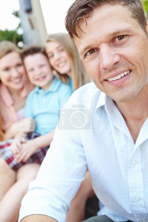 Téléchargez les photos : Nous sommes une famille très unie. Beau père avec sa famille assise derrière lui en plein air - en image libre de droit