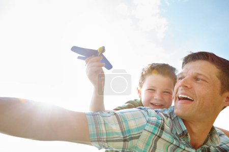 Téléchargez les photos : Laisse-le monter en flèche. Un petit garçon mignon jouant avec un avion tout en étant porté sur ses pères dos - en image libre de droit