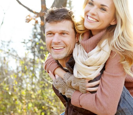 Téléchargez les photos : Amusez-vous sous le soleil d'automne. Un homme heureux derrière sa petite amie tout en passant du temps dans les bois - en image libre de droit