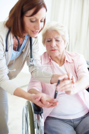 Téléchargez les photos : Les connaissances sont habilitantes - Soins aux aînés. Une infirmière soignante aide une patiente âgée à vérifier elle-même son taux de sucre dans le sang - en image libre de droit