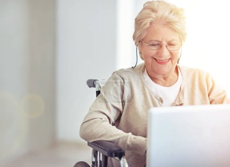 Foto de Conectando con su familia. una mujer mayor usando un portátil mientras está sentada en una silla de ruedas - Imagen libre de derechos